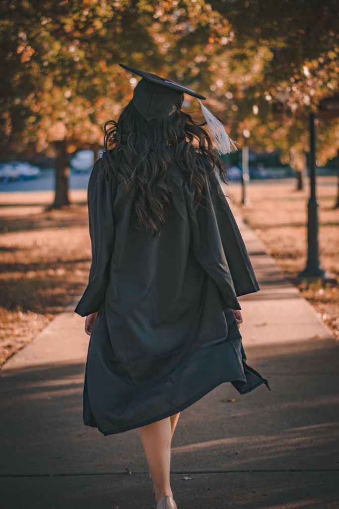 Woman in cap and gown walking away from the camera